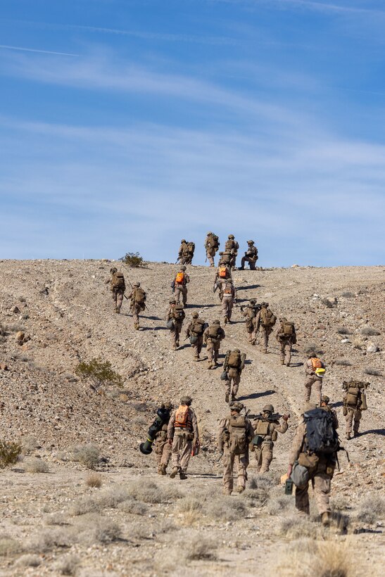 U.S. Marines with 2nd Battalion, 4th Marine Regiment, 1st Marine Division, hike to a higher position during a ground assault as part of a Marine Air-Ground Task Force Distributed Maneuver Exercise as part of Service Level Training Exercise 2-24 around Gays Pass training area, at Marine Corps Air-Ground Combat Center, Twentynine Palms, California, Feb. 14, 2024. MDMX prepares Marines for future conflicts by conducting offensive and defensive live-fire and maneuver training scenarios within an austere training environment. (U.S. Marine Corps photo by Lance Cpl. Anna Higman)