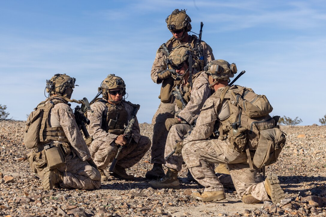 U.S. Marines with 2nd Battalion, 4th Marine Regiment, 1st Marine Division, are briefed at the halfway point during a ground assault as part of a Marine Air-Ground Task Force Distributed Maneuver Exercise as part of Service Level Training Exercise 2-24 around Gays Pass training area, at Marine Corps Air-Ground Combat Center, Twentynine Palms, California, Feb. 14, 2024. MDMX prepares Marines for future conflicts by conducting offensive and defensive live-fire and maneuver training scenarios within an austere training environment. (U.S. Marine Corps photo by Lance Cpl. Anna Higman)