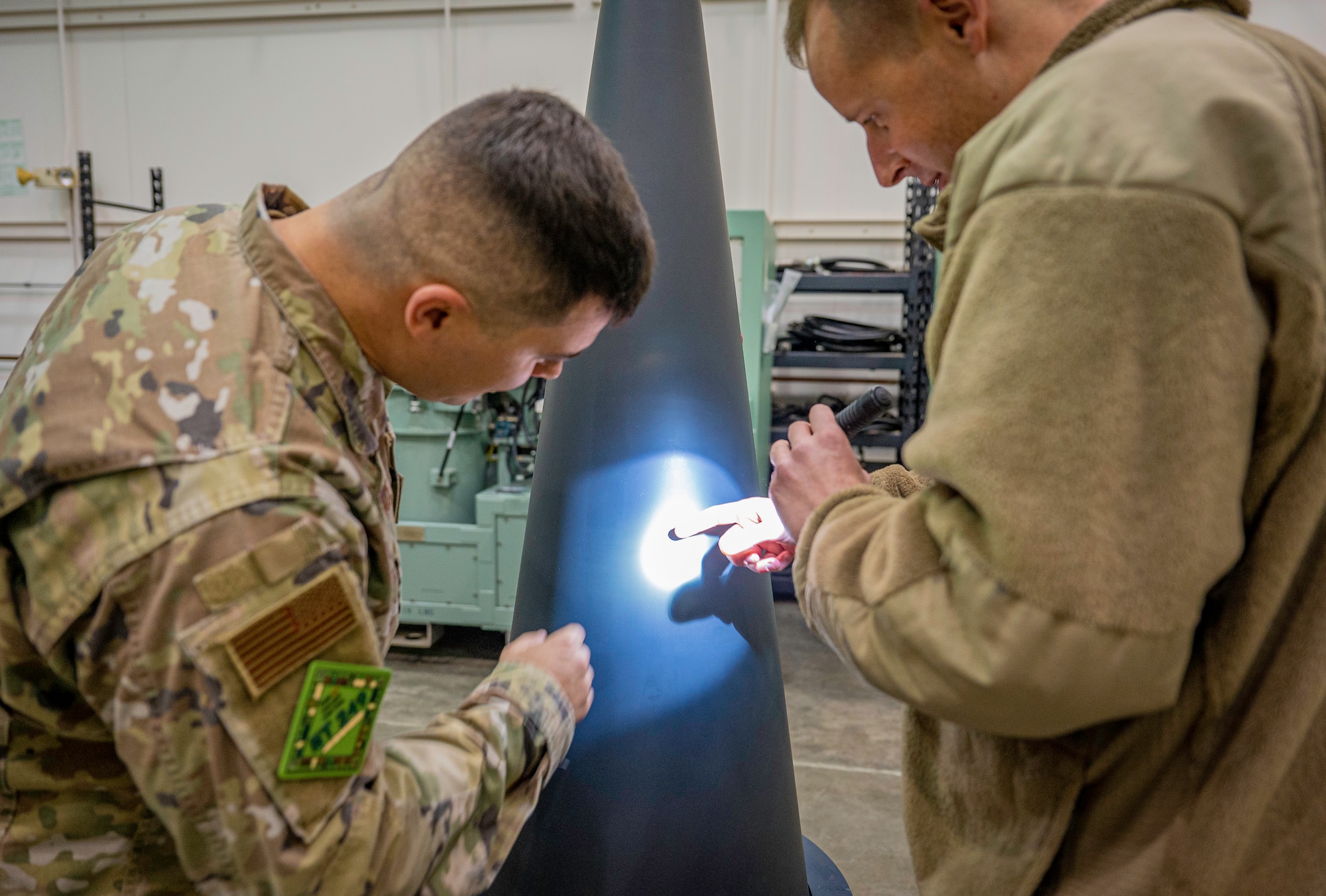 Two people working on a missile’s components