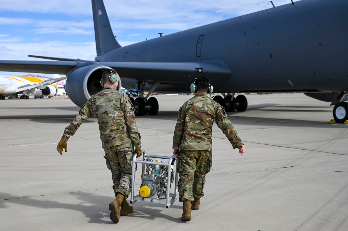 Airmen carry a fuel kit to a jet.