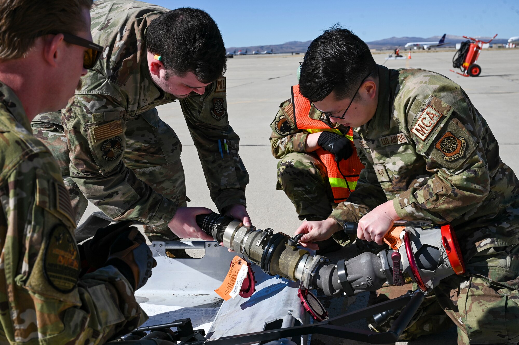 Airmen connect a fuel hose.