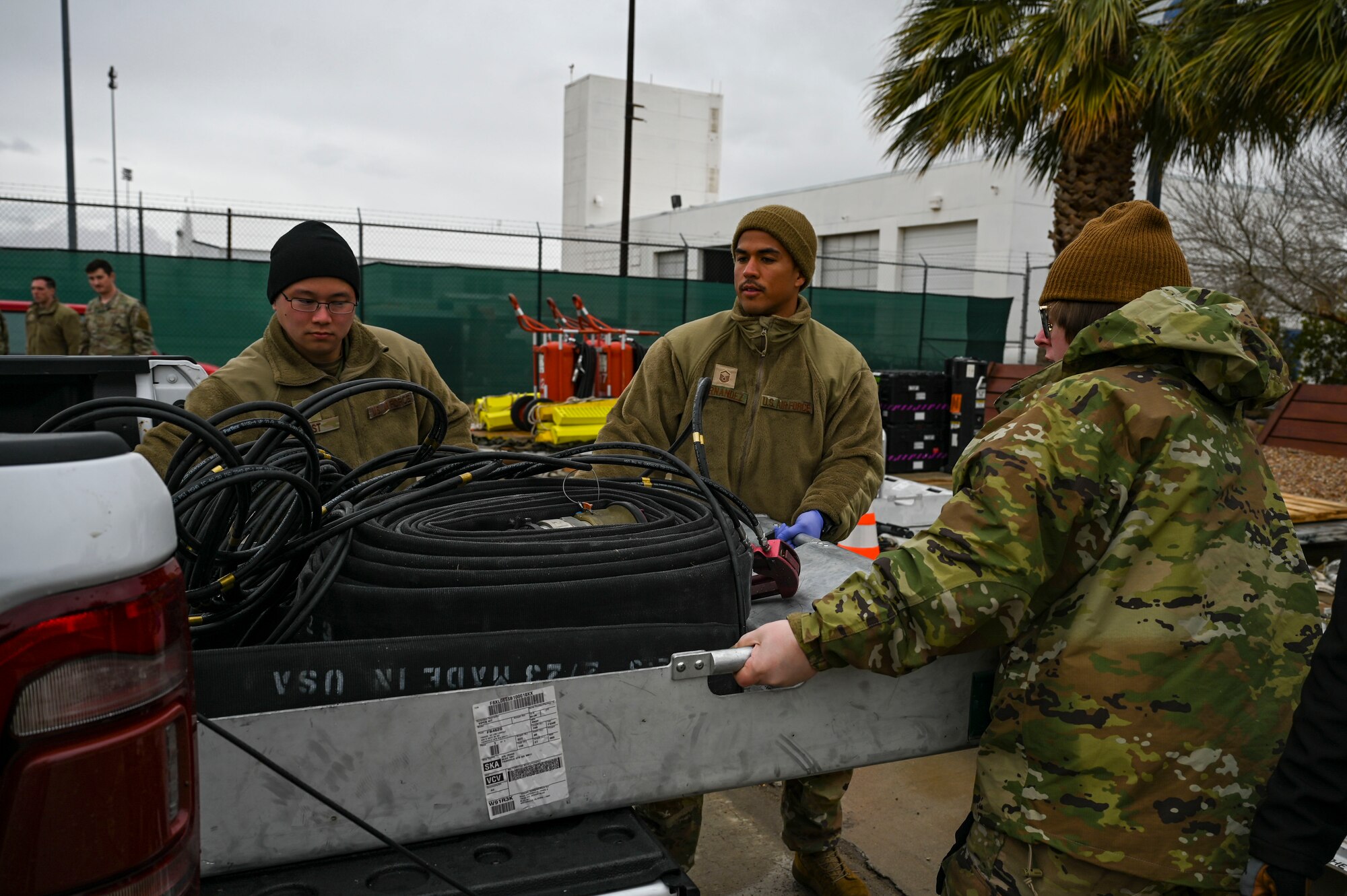 Airmen load a metal carrier into a truck.