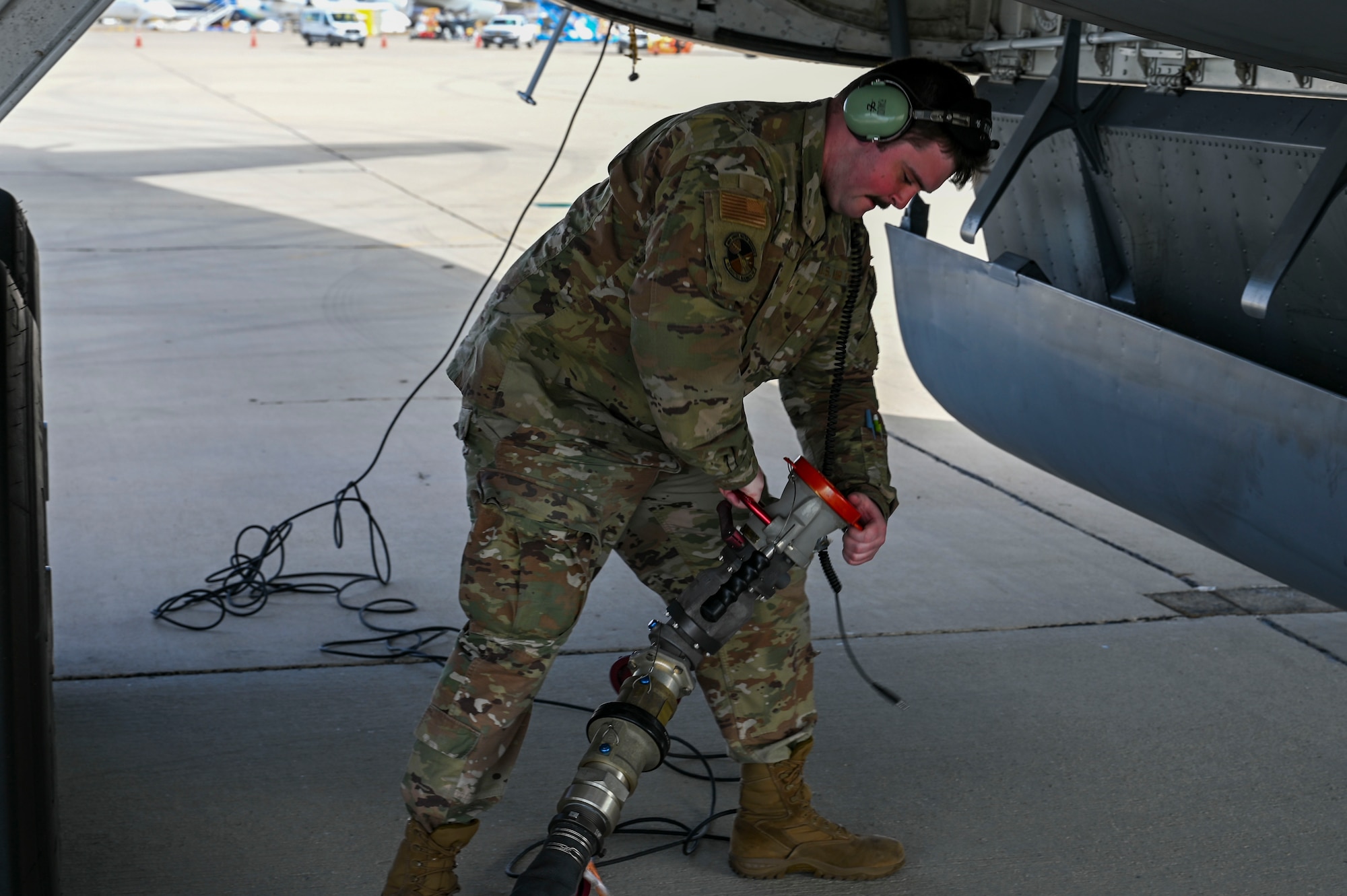 An Airman drags a fuel hose to a jet.