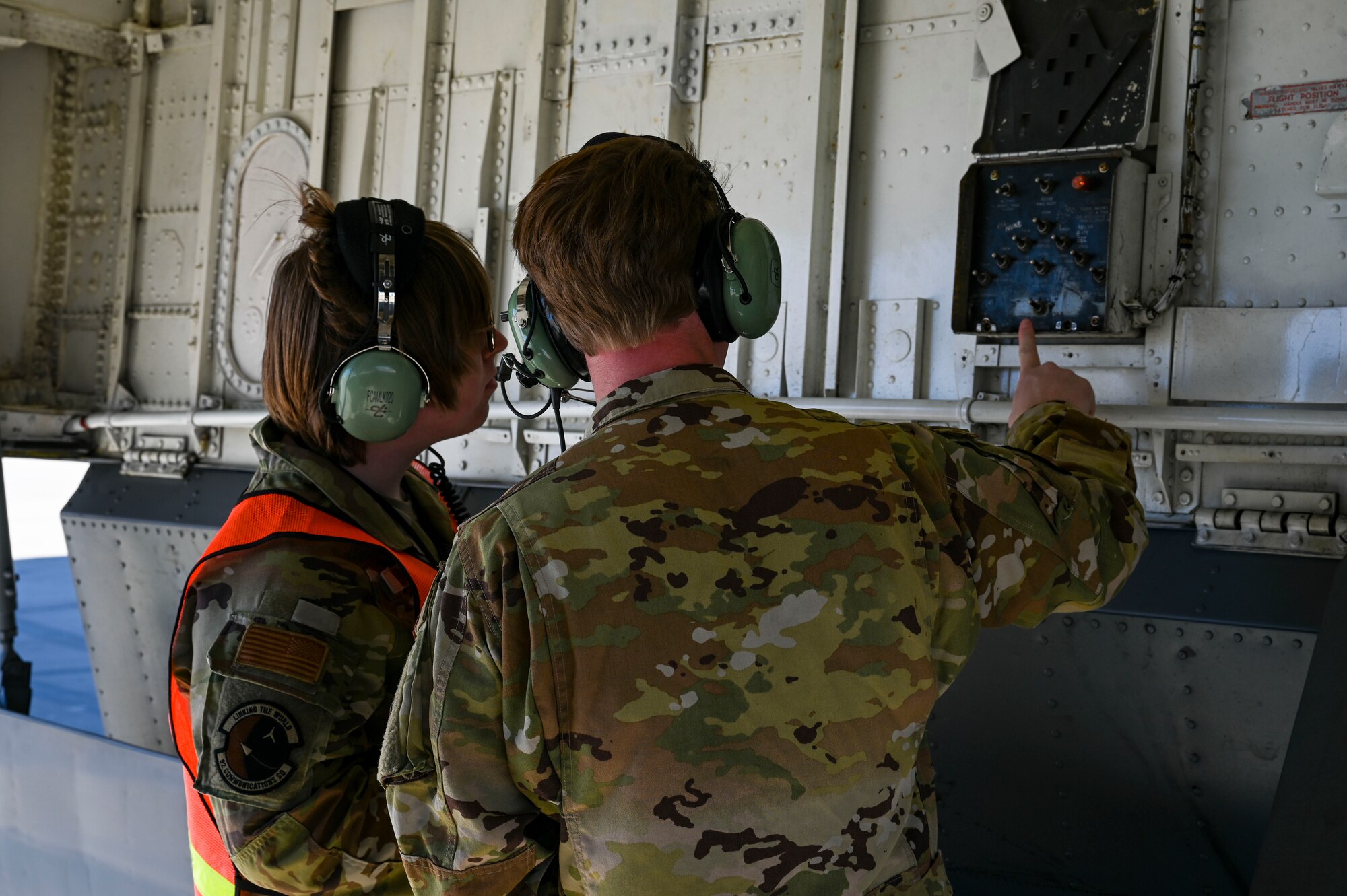 An Airman shows another Airman how to operate a fuel switch on a jet.