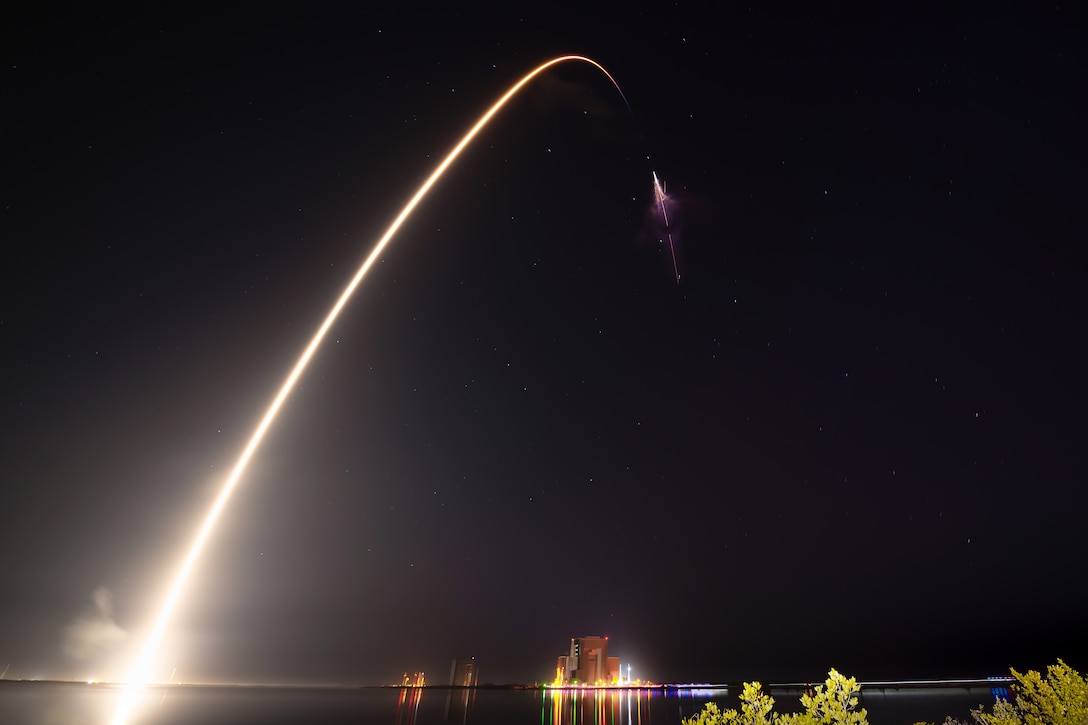 A rocket launches at night leaving behind a plume of light against the dark sky.