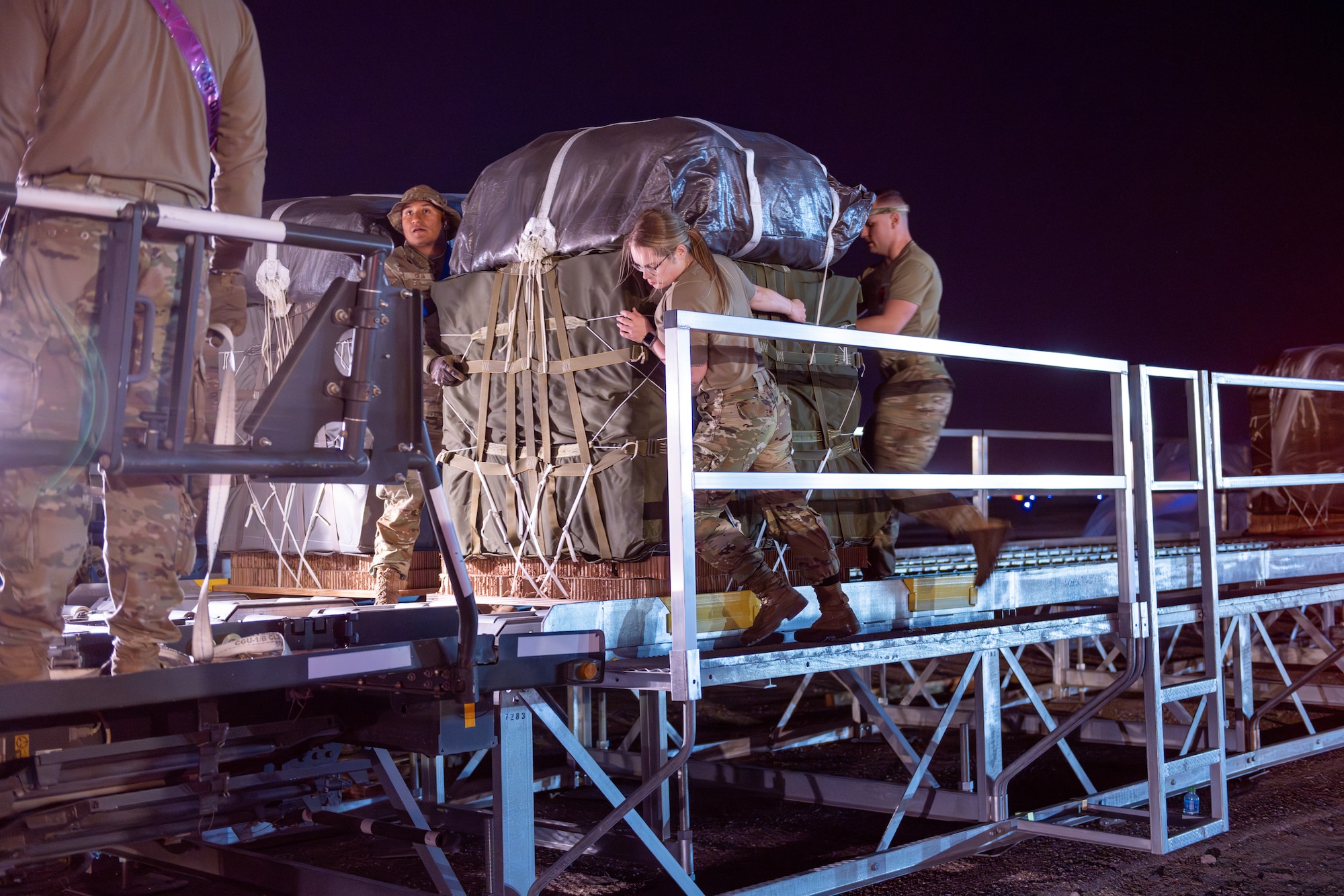 Aerial Port Airmen and U.S. Army parachute riggers usher in pallets of humanitarian aid destined for Gaza.
