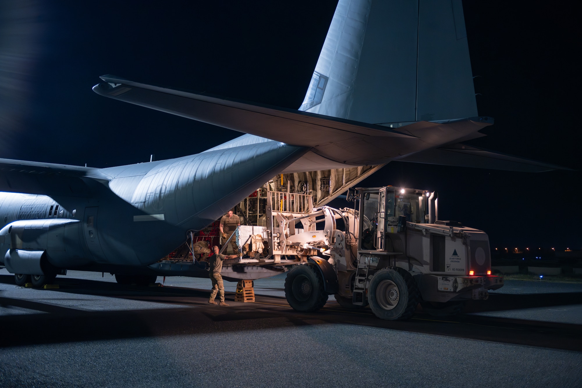 Loadmasters and aerial porters load a buffer stop assembly onto a C-130J Super Hercules prior to loading pallets of humanitarian aid destined for Gaza.