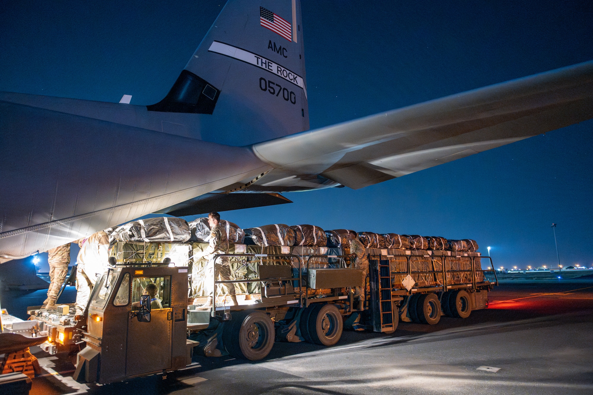 Airmen and Soldiers load pallets of humanitarian aid aboard a C-30J Super Hercules.