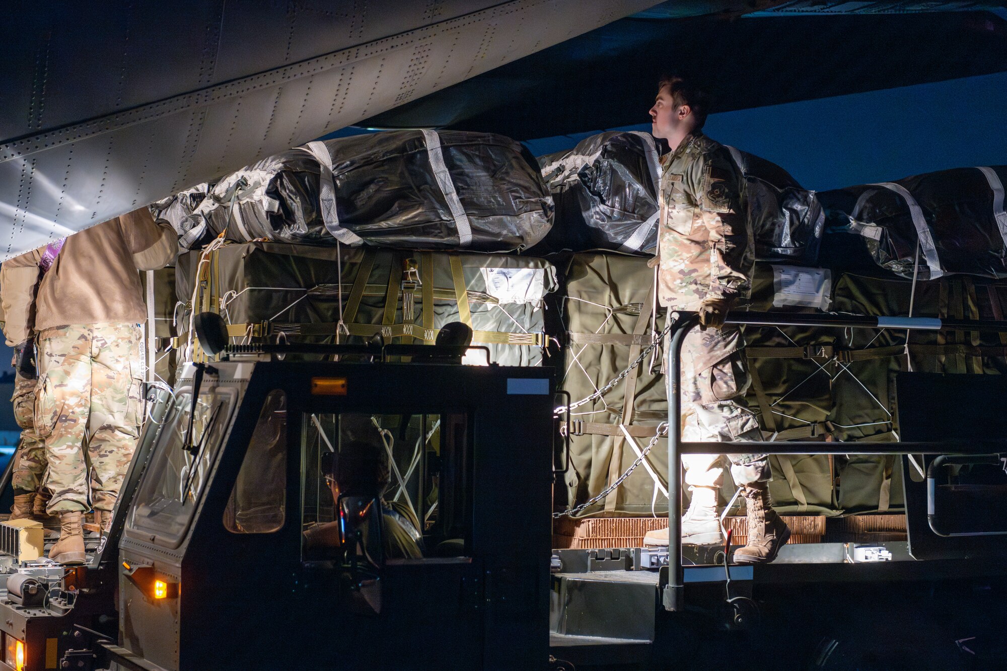 Airmen and Soldiers load pallets of humanitarian aid onto a C-130J Super Hercules.