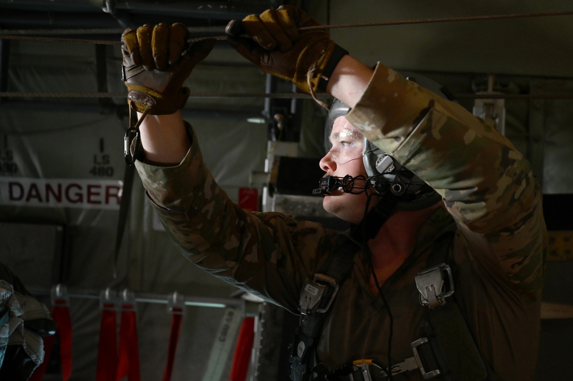 A loadmaster prepares to release humanitarian aid pallets of packaged food over Gaza.