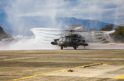 A UH-60 Black Hawk helicopter flown by Chief Warrant Officer 4 Rick Dean, assigned to U.S. Army Aviation Battalion–Japan, is sprayed with water after Dean's final flight at Camp Zama's Kastner Airfield in Japan, Dec. 1, 2023. Dean served 26 years in the Army, much of them as a helicopter pilot. (Photo Credit: Esther Dacanay, U.S. Army Japan Public Affairs)