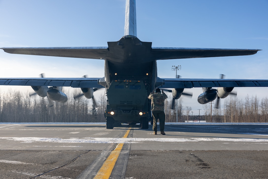 New York Air National Guard Tech. Sgt. Eric Junquera marshals a High Mobility Artillery Rocket System (HIMARS) into a C-130 Hercules aircraft in support of Arctic Edge 24 at Eielson Air Force Base, Alaska, Feb. 24, 2024. AE24 is an annual defense exercise for the U.S. Northern Command emphasizing Joint Force operations in an extreme cold weather and high latitude environment and is designed to demonstrate Globally Integrated Layered Defense in the Arctic. (U.S. Air National Guard photo by Technical Sergeant Madison Scaringe)
