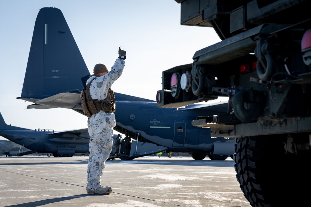 A U.S. Marine with Fox Battery, 2nd Battalion, 14th Marine Regiment, 4th Marine Division, Marine Forces Reserve directs a M142 High Mobility Artillery Rocket System (HIMARS) to begin onloading onto a C-130J Hercules during a HIMARS Rapid Infiltration, also known as a HIRAIN, during exercise Arctic Edge 2024 at Eielson Air Force, Alaska, Feb. 24, 2024. The HIRAIN training demonstrated Marine Forces Reserve’s ability to rapidly deploy the HIMARS to meet and deter any threats in any environment, including harsh arctic environments. Arctic Edge 2024 (AE24) is a U.S. Northern Command-led homeland defense exercise demonstrating the U.S. military’s capabilities in extreme cold weather, joint force readiness, and U.S. military commitment to mutual strategic security interests in the arctic region. (U.S. Marine Corps photo by Lance Cpl. Madisyn Paschal)