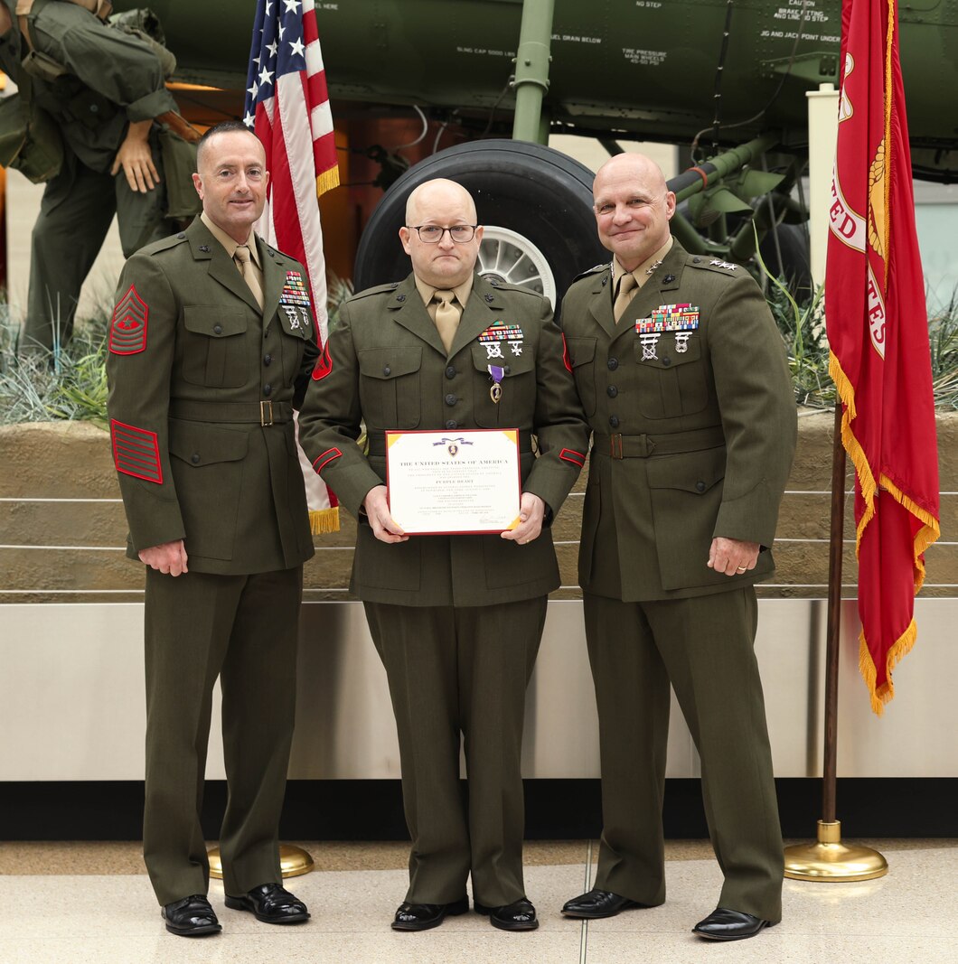 Retired U.S. Marine Corps Lance Cpl. Jeremy R. Williams, a Texas native, center, stands with Sgt. Maj. Christopher J. Adams, sergeant major of 4th Marines Division, left, and Lt. Gen. David G. Bellon, commander of U.S. Marine Corps Forces Reserve and U.S. Marine Corps Forces South, right, during his Purple Heart ceremony at the National Museum of the Marine Corps, Triangle, Virginia, March 2, 2024. Williams suffered a traumatic brain injury directly related to an improvised explosive device incident in Ramadi, Iraq, on May 15, 2006. (U.S. Marine Corps photo by Lance Cpl. David Brandes)