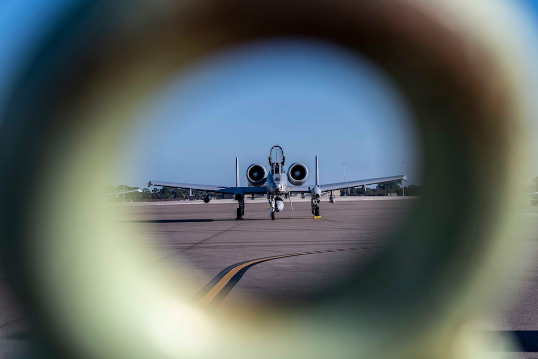 An A-10 is shot through a metal ring that is part of a towable fire extinguishing bottle.