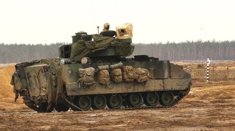 Soldier peers ahead from a tank turret.