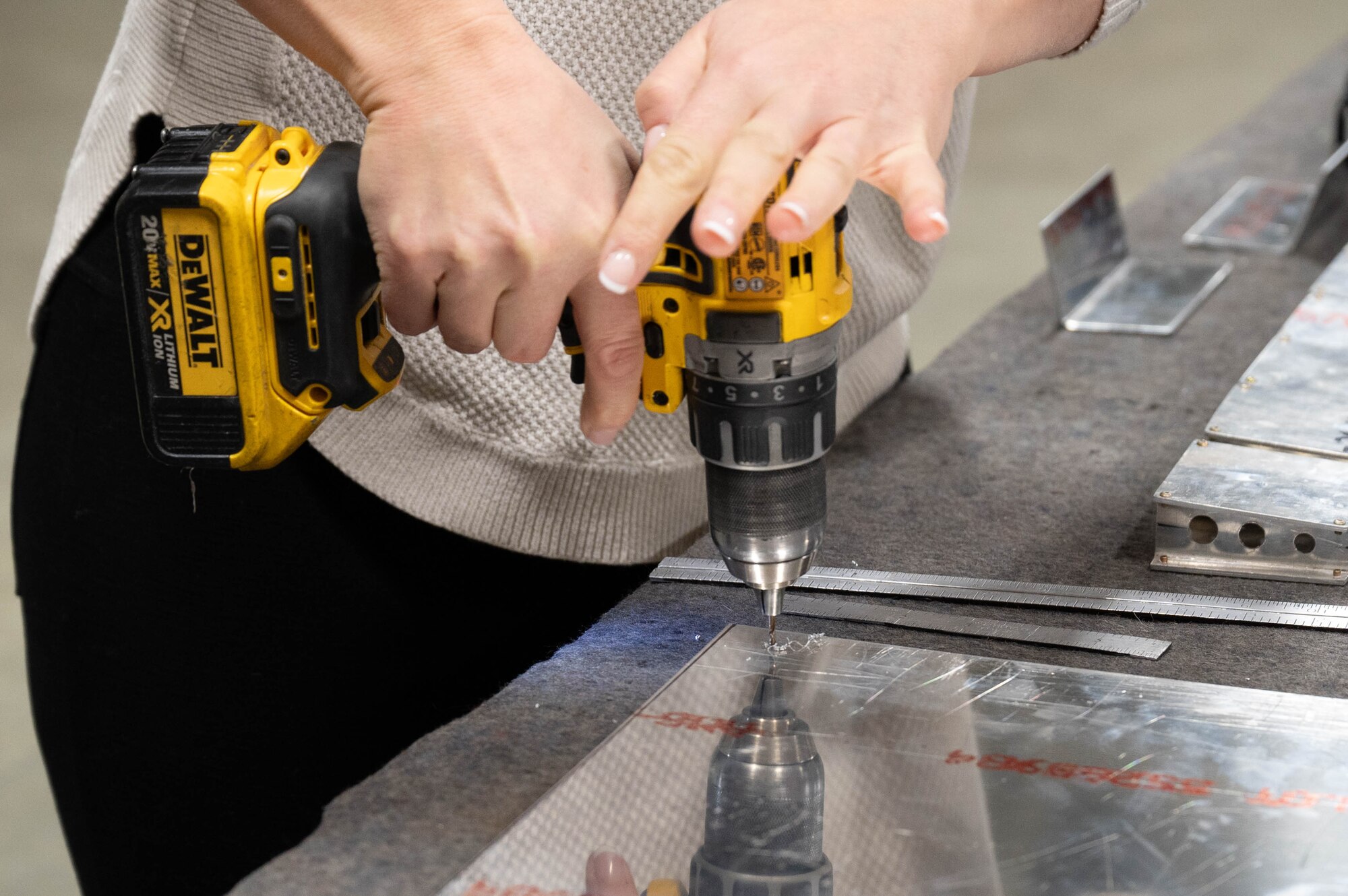 A 354th Maintenance Squadron spouse drills into a piece of sheet metal as part of a hands-on demo during the 354th MXS spouses' open house March 1, 2024 at Eielson Air Force Base,