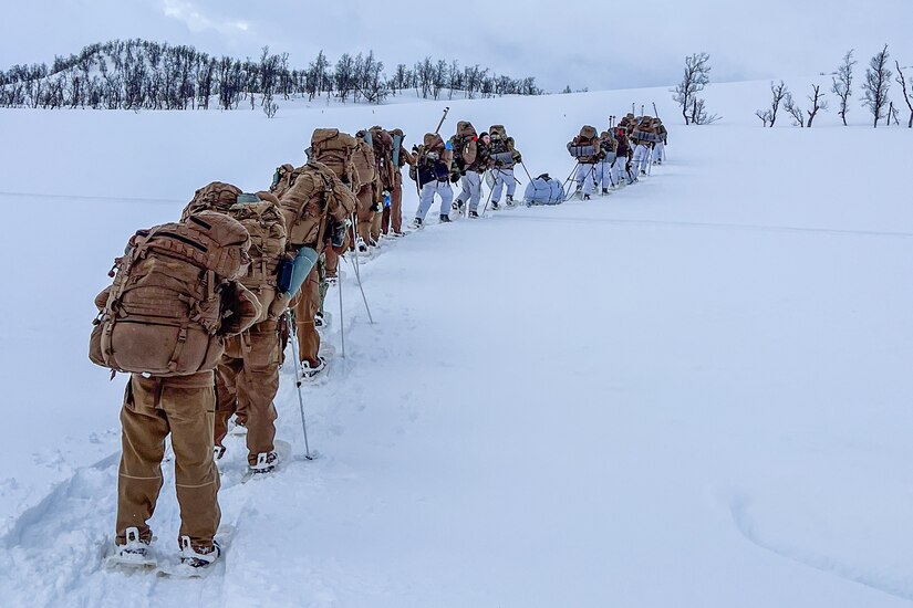 U.S. and Norwegian sailors hike a snowy mountain.