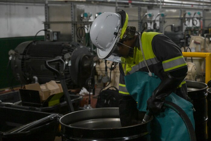 A member in support of Joint Task Force-Red Hill (JTF-RH) guides a drainage line into a fuel drum to remove residual fuel from the Underground Pump House located on Joint Base Pearl Harbor-Hickam (JBPHH), Hawaii, March 4, 2024, where personnel are preparing to disconnect the Red Hill Bulk Fuel Storage Facility (RHBFSF) from the Underground Pump House.