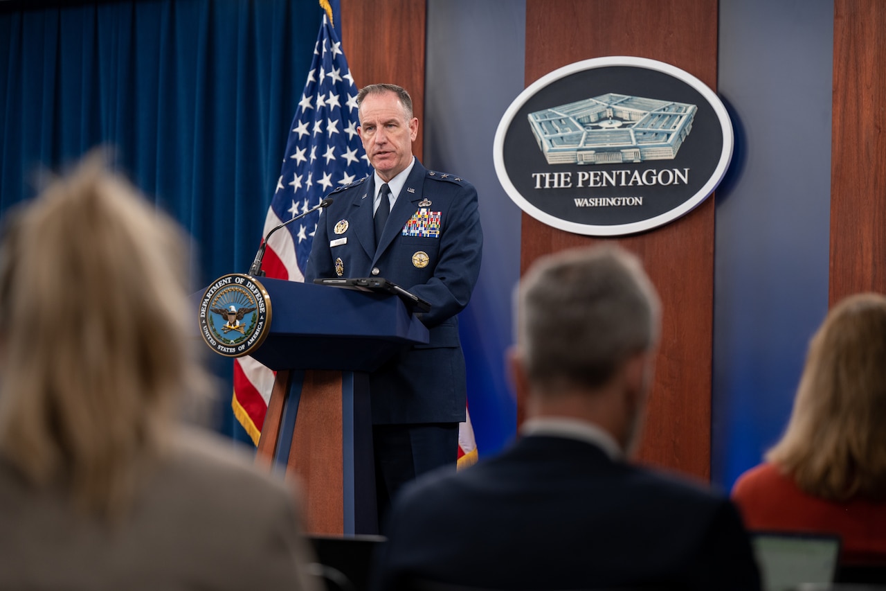 A man in a military uniform stands behind a lectern. The sign behind him indicates that he is at the Pentagon.