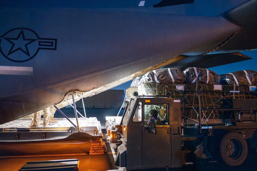 A vehicle loads cargo onto the back of an aircraft.