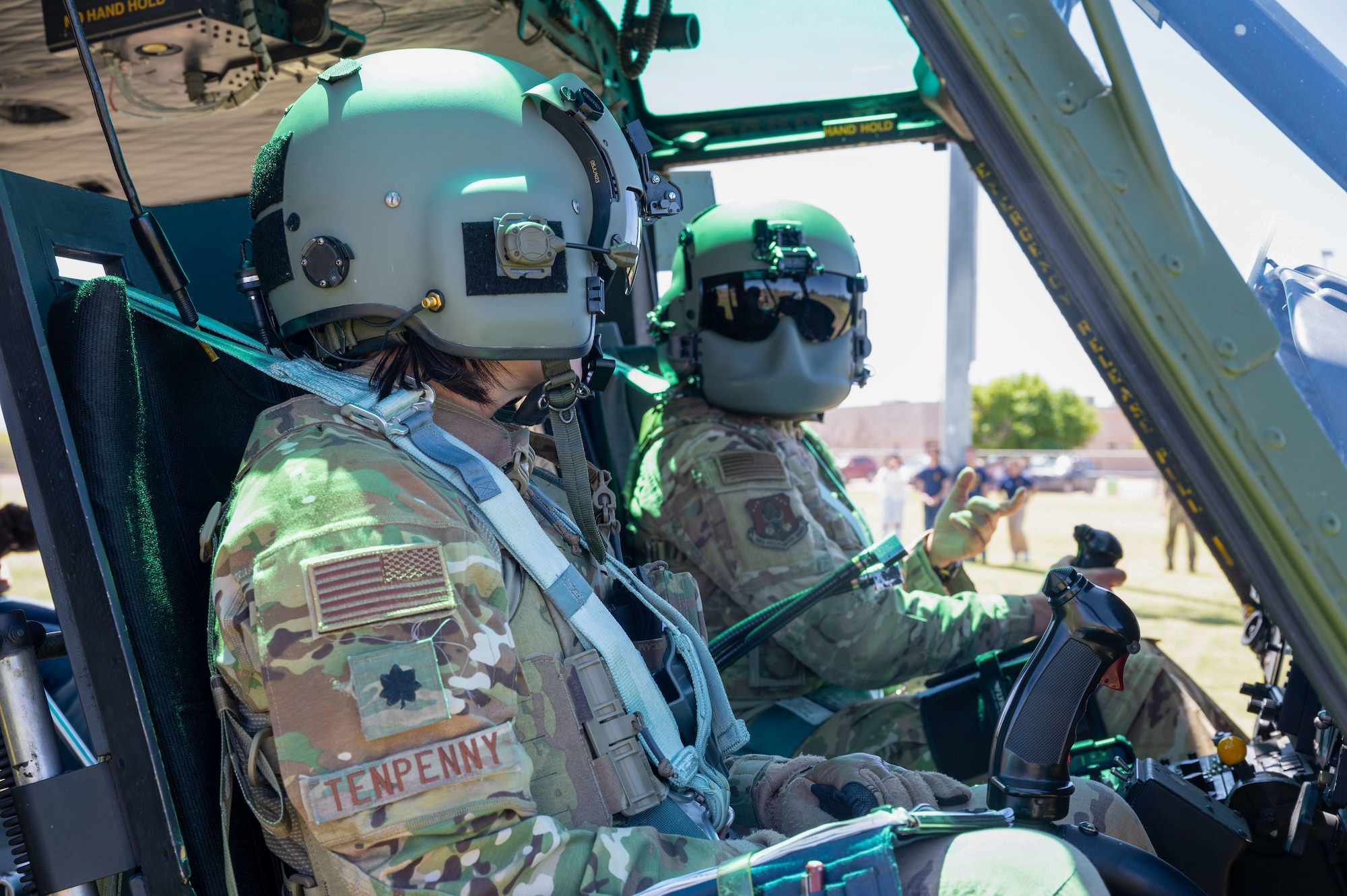 Two helicopter pilots sit in a cockpit preparing for takeoff.