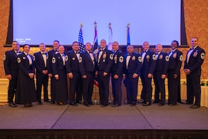 Chief master sergeants pose for a photo on a stage.