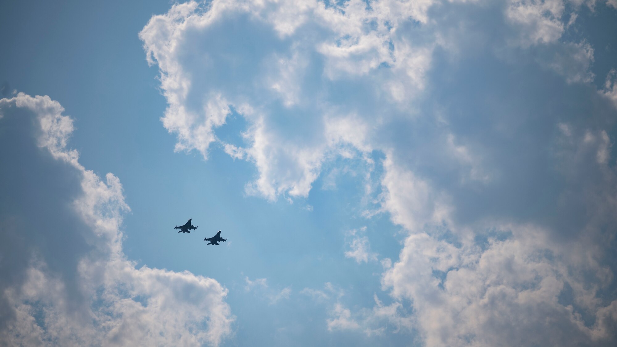 Two F-16 Fighting Falcons soar beside each other after participating in a maritime strike exercise scenario