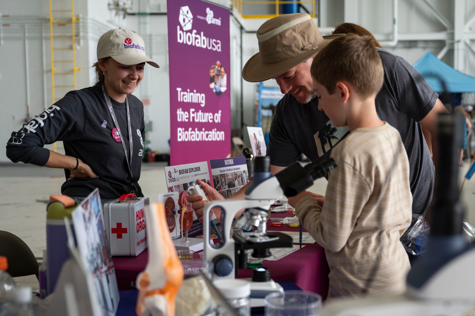 Visitors learn about biofab technologies at a booth in an aircraft hangar