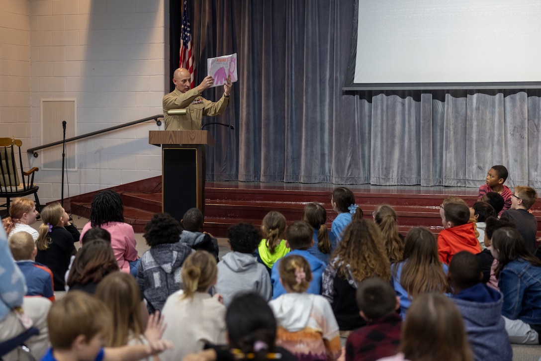 Lt. Col. Brian T. Everett, commanding officer, Headquarters and Service Battalion, 2nd Marine Logistics Group, reads a book to elementary students at Parkwood Elementary School during Readers Make Leaders Day as part of Reading Across America Week in Jacksonville, North Carolina, Feb. 27, 2024. On the last Friday of every month, at least 10 Marines with H&S Battalion volunteer to be role models and mentors for students at Parkwood Elementary School through the “Adopt a School” program, strengthening community relationships between the Marine Corps and the public. (U.S. Marine Corps photo by Lance Cpl. Jessica J. Mazzamuto)