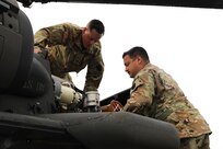 U.S. Army Sgt. Devin Smerlick, a crew chief with Charlie Company, 2-104th General Support Aviation Battalion, 28th Expeditionary Combat Aviation Brigade assists Capt. Stephan Pernelli with pre-flight checks at Fort Indiantown Gap, July 25, 2023. (U.S. Army National Guard Photo by 2nd Lt. Kate Kramer)