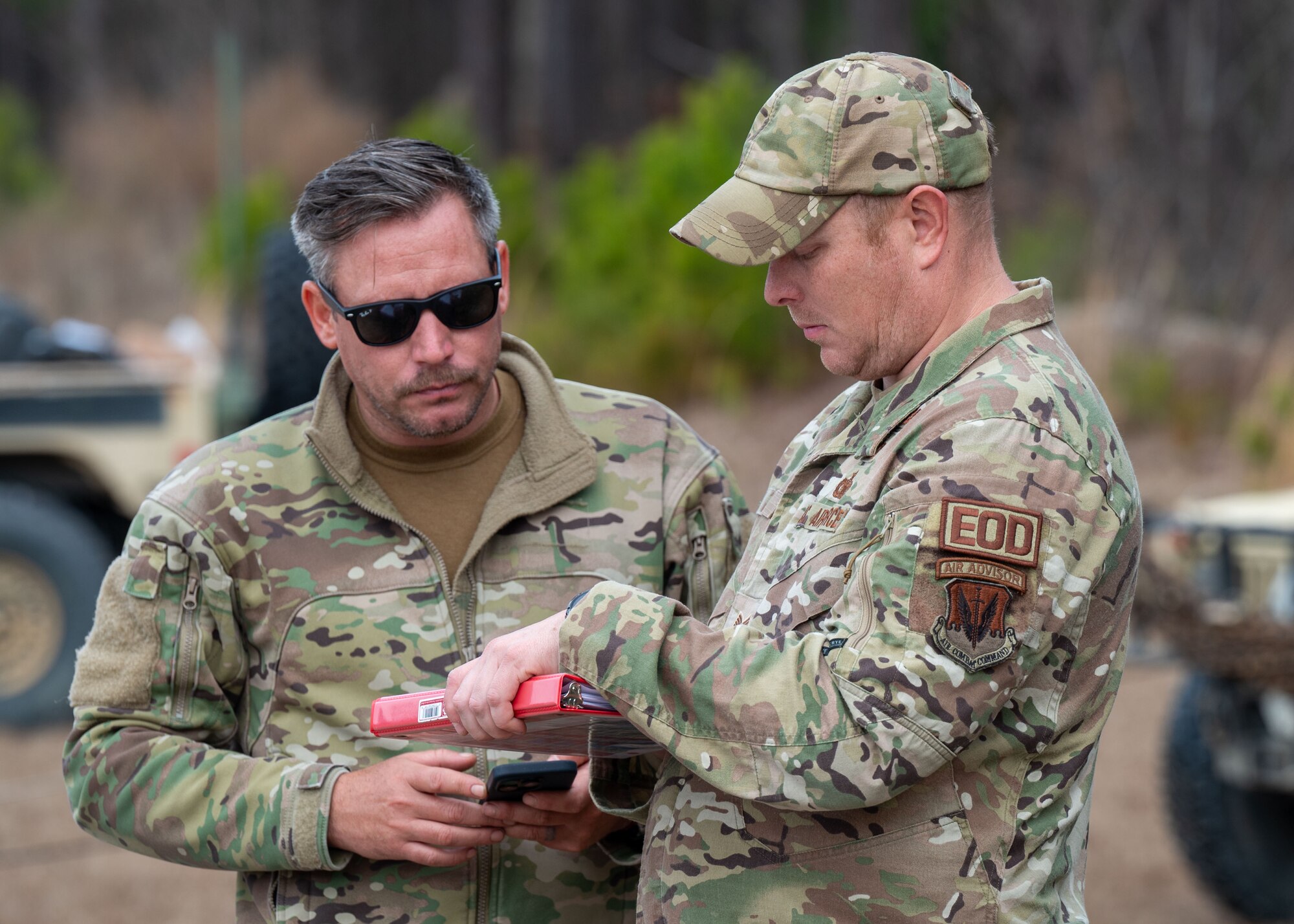 Two men look at a notebook.