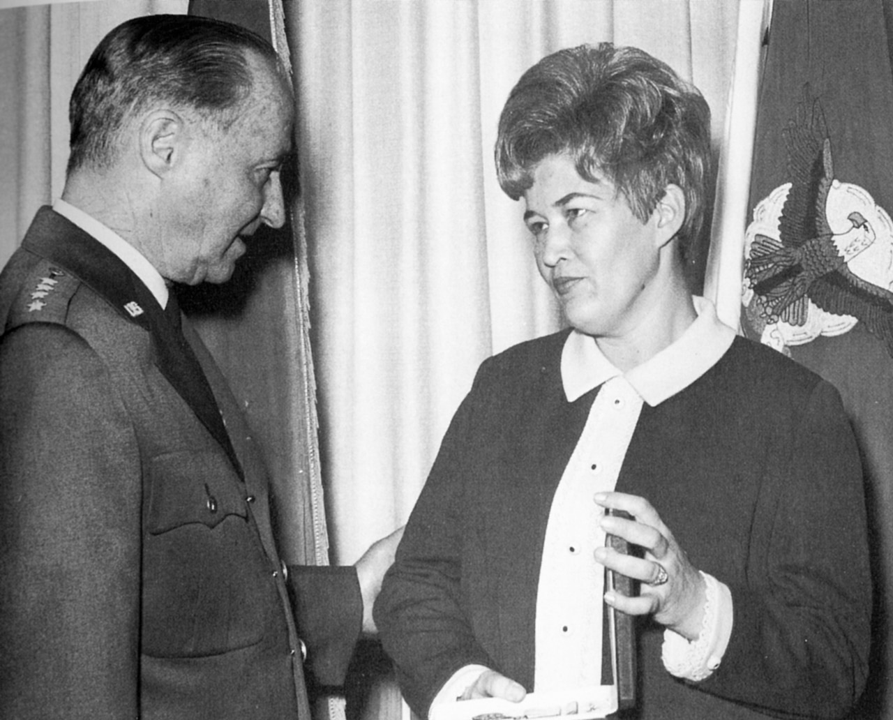 A woman holds a box in her hands while looking at the man who gave it to her.