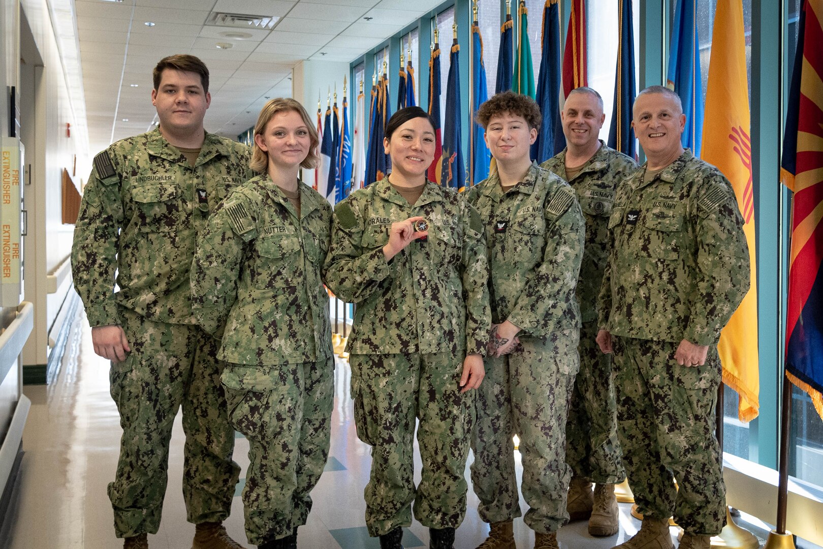Hospital Corpsman Second Class Nancy Morales, center, received a Coin from Navy Capt. Sean Barbabella, Commander of Naval Health Clinic Cherry Point, in recognition of her initiative and expertise on Tuesday, March 5, 2024.
Faced with low staffing over the 2023 holiday period, Morales, assigned to the clinic’s Readiness Department, developed a new system expediting service members’ Periodic Health Assessments, resulting in the rapid review of over 200 in a period of two weeks.