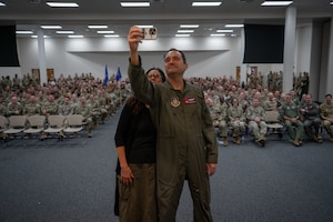 Deputy Commanders stands in front of group of Airmen and takes a selfie.