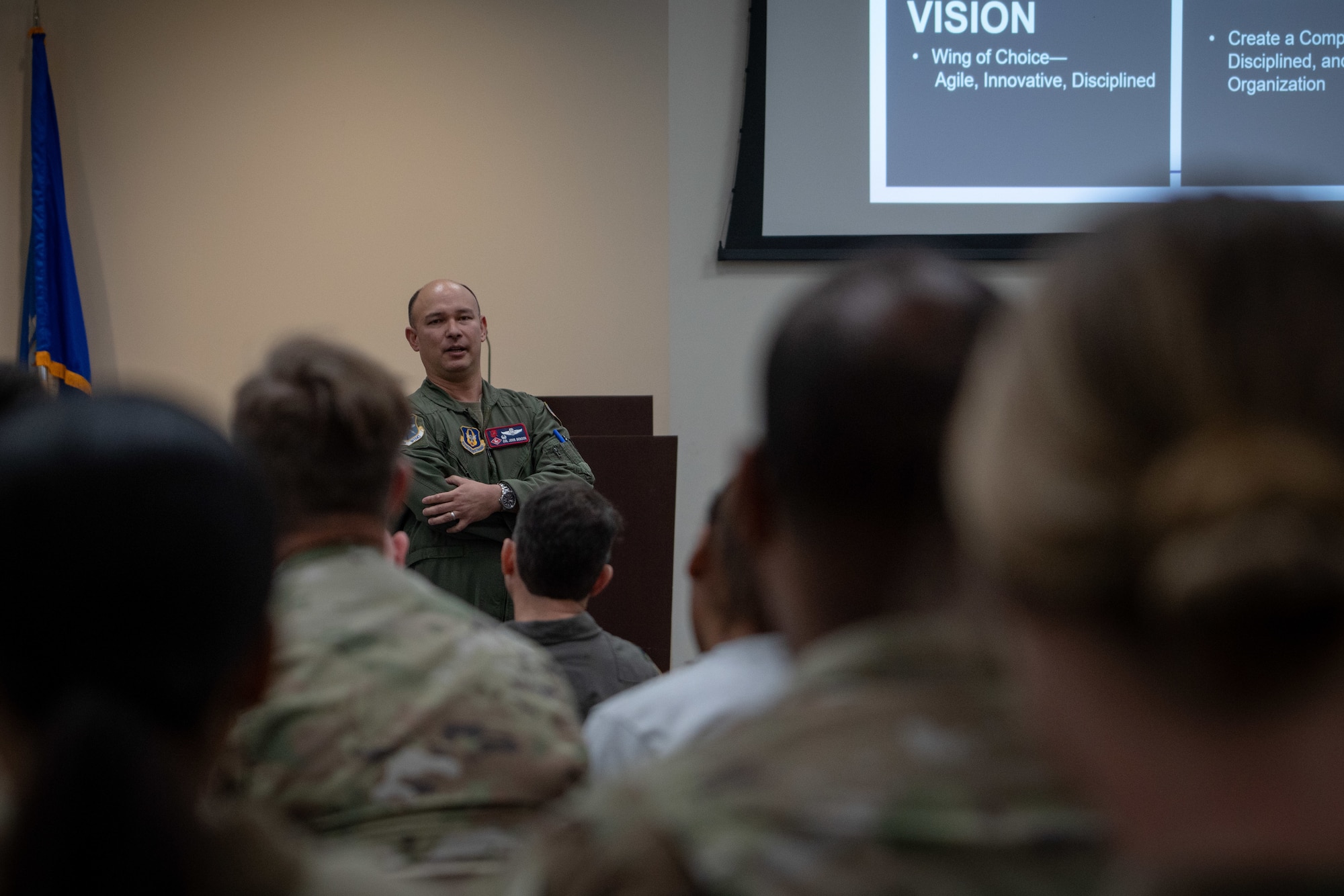 Wing commander stands in front of group of Airmen.