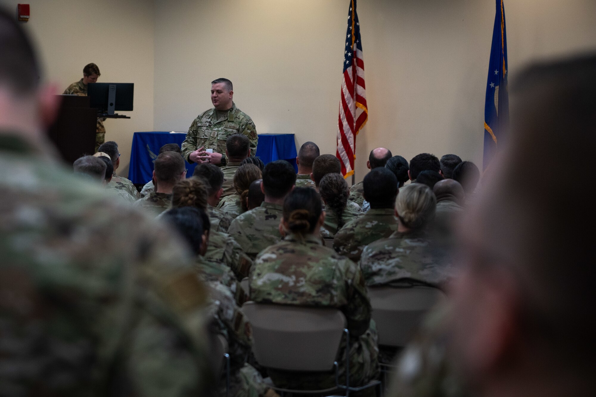 Command Chief stands in front of group of Airmen.