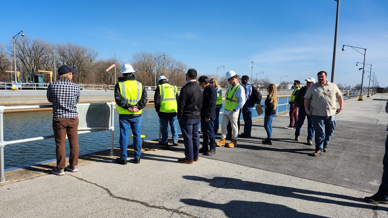 Employees in hardhats and safety vests lock into the water at the lock.