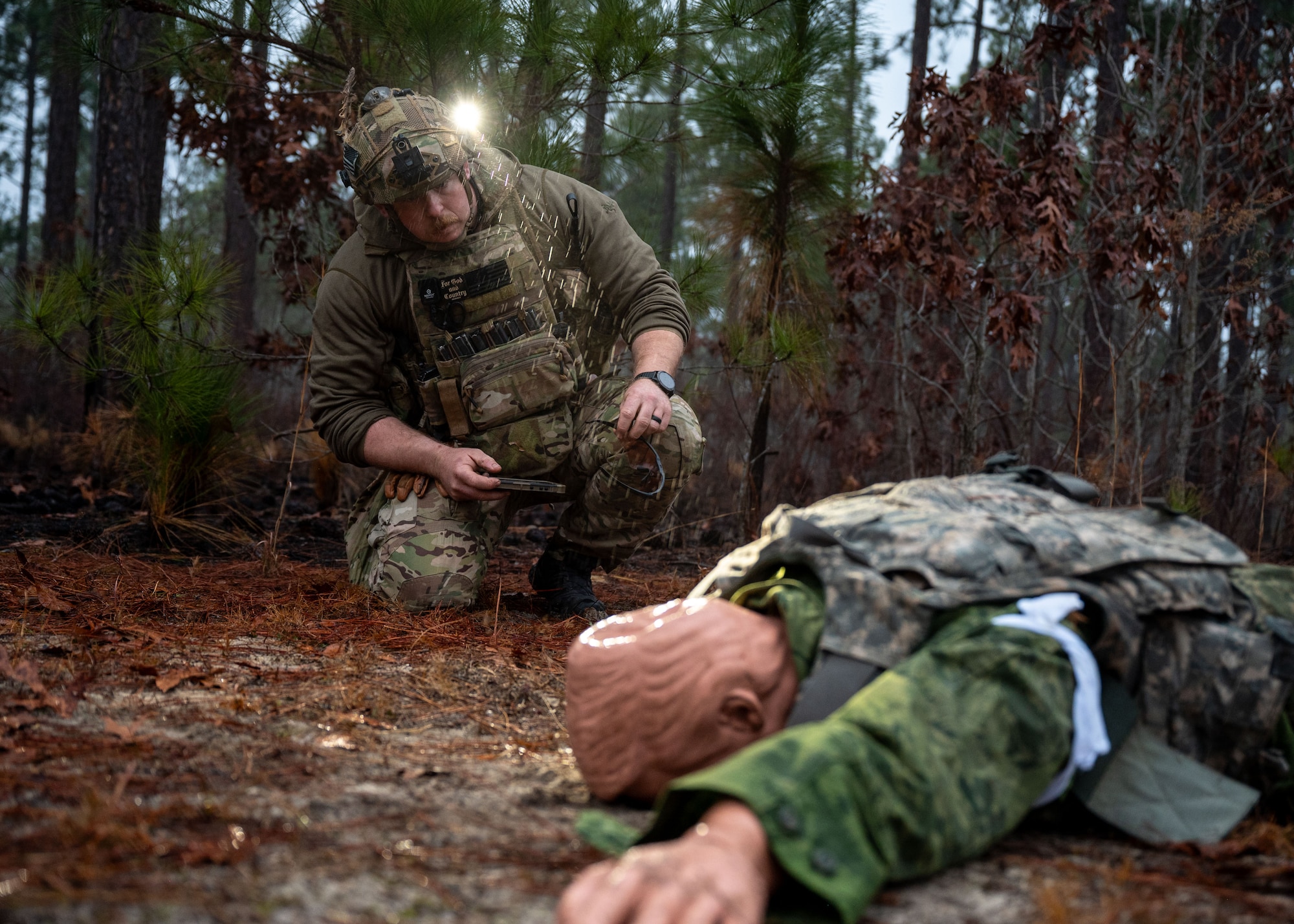 A man looks at a training mannequin laying in the dirt.