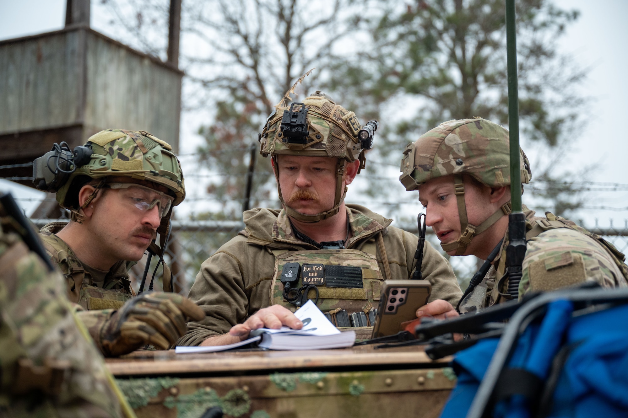 Three men look at a notebook.