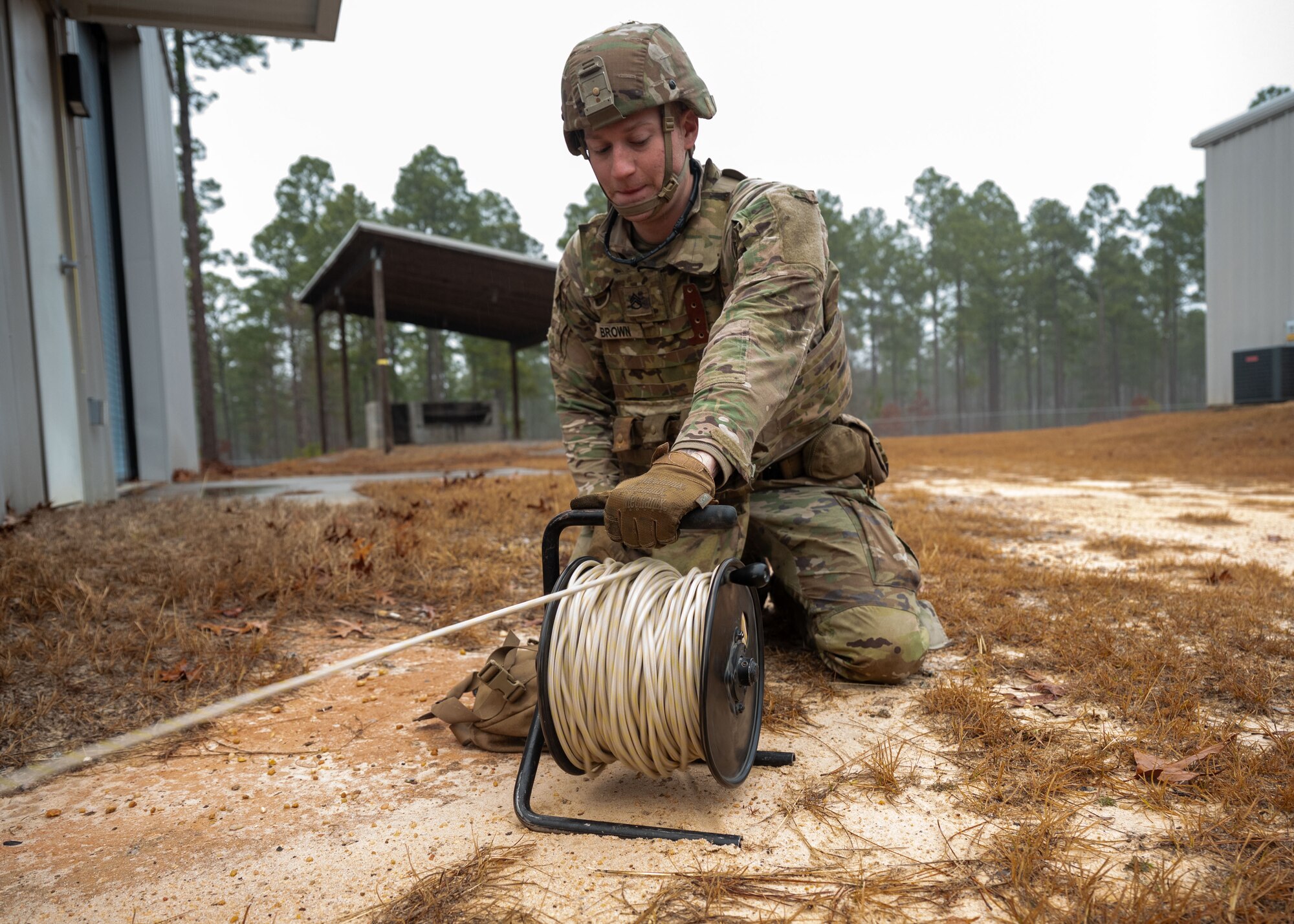 A man kneels over a reel of rope.