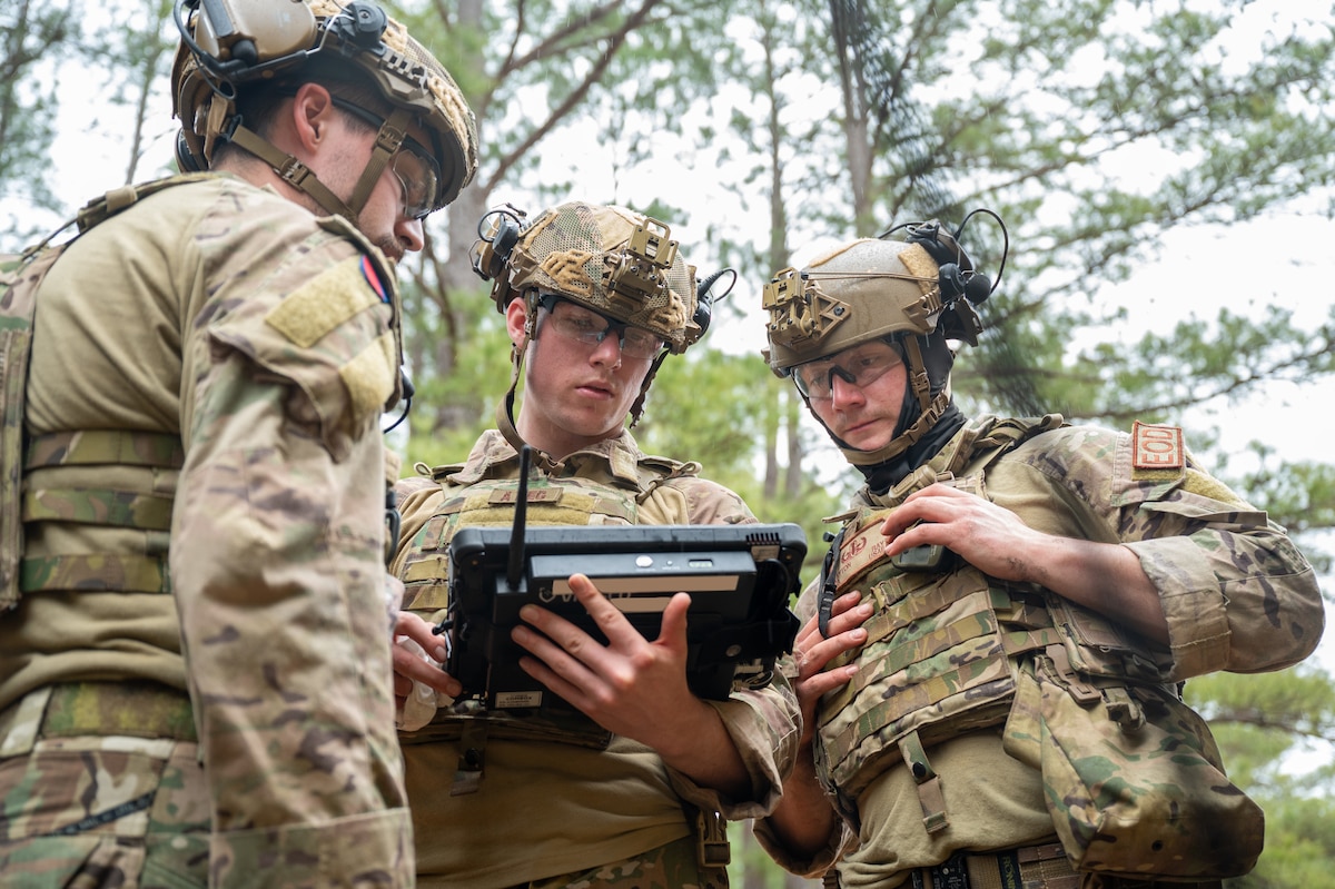 Three men look at an imaging device between them.