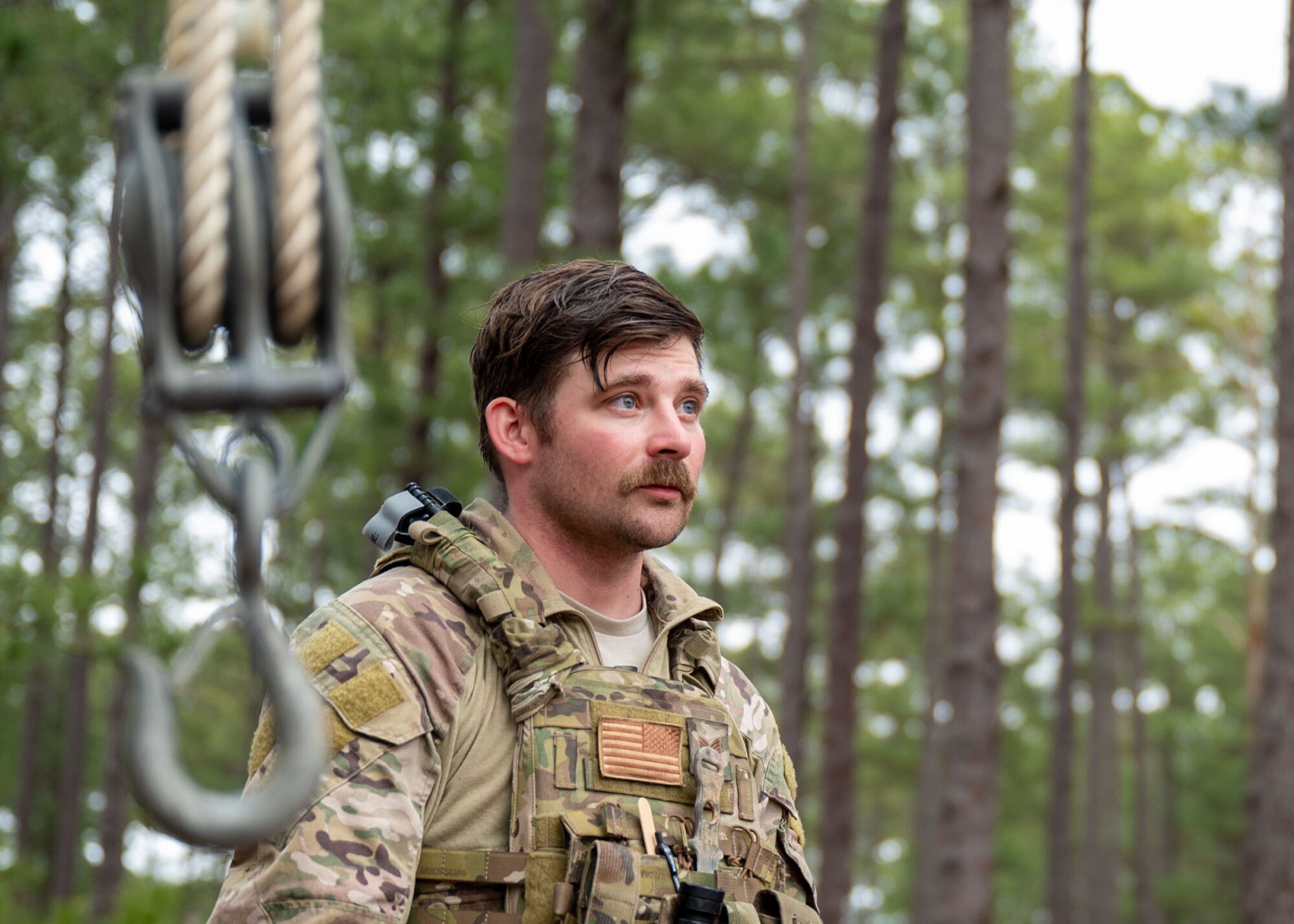 A man looks off screen behind a hook hanging from a pulley.