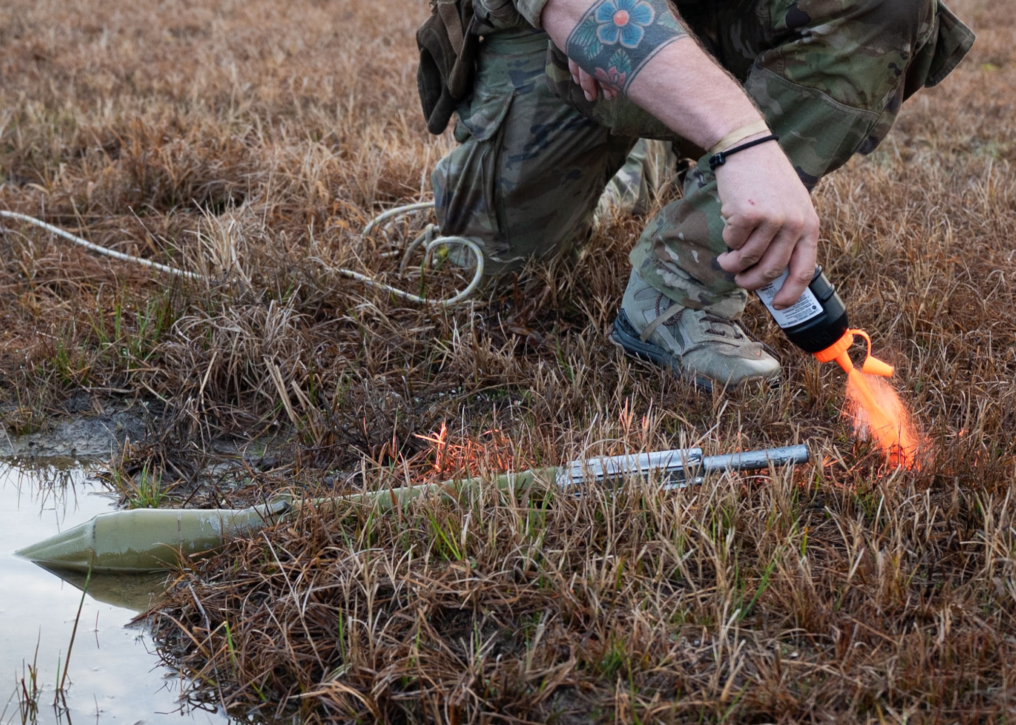 A close up of a hand squeezing orange marking chalk from a bottle on a training munition.