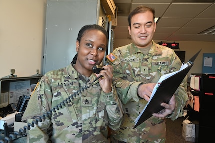 U.S. Army Staff Sgt. Belita Lynum, aviation operations specialist, and CW2 Christopher Alora, an operations officer at the District of Columbia Army National Guard Aviation Support Facility, talk on the radio while maintaining logs on incoming and outgoing flights, at Davison Army Airfield, Feb. 3, 2024.  DCARNG Aviation is comprised of four different units with women visibly represented in all sections to include pilots, maintainers, supply, operations, administration, and flight paramedics.