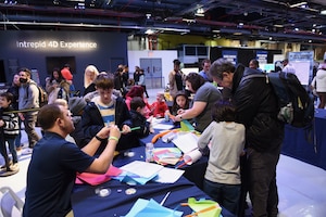 Engineers from Naval Air Warfare Center Aircraft Division teach children how to build paper airplanes during Kids Week at the Intrepid Aircraft Carrier Museum in New York City, Feb. 22-24. The event gave children a chance to learn about the fields of Science, Technology, Engineering, Arts and Math through a variety of exhibits and demonstrations. (Courtesy photo)