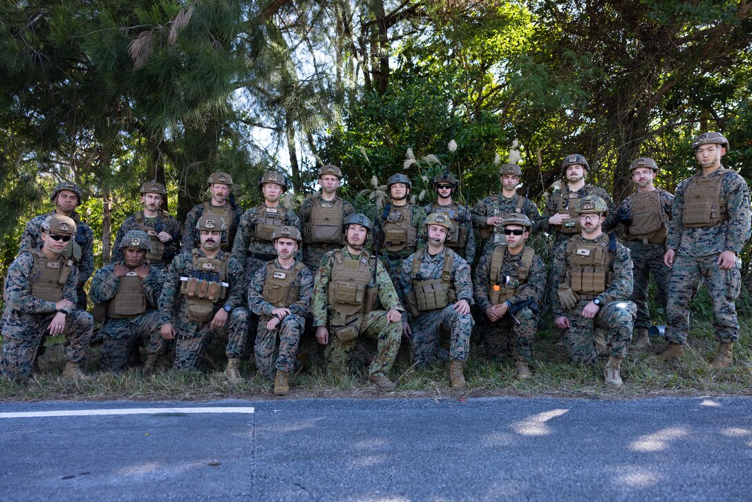 U.S. Marines with 5th Air Naval Gunfire Liaison Company, III Marine Expeditionary Force Information Group, and Japan Ground Self-Defense Force Master Sgt. Tomoya Tasaki and Sgt. 1st Class Akira Wada with Fire Leading Company, Field Artillery Battalion, Amphibious Rapid Deployment Brigade, pose for a group photo after a tactical air control party training event on Camp Hansen, Okinawa, Japan, December 15, 2023. 5th ANGLICO trained with Japan Ground Self-Defense Force service members to enhance their partnership and force capabilities. TACP enables Marines to control and operate air space, plan and execute fire missions, and engage enemy forces. (U.S. Marine Corps photo by Cpl. Kira Ducato)