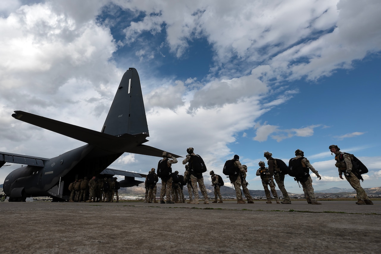 Service members stand together near a large aircraft.