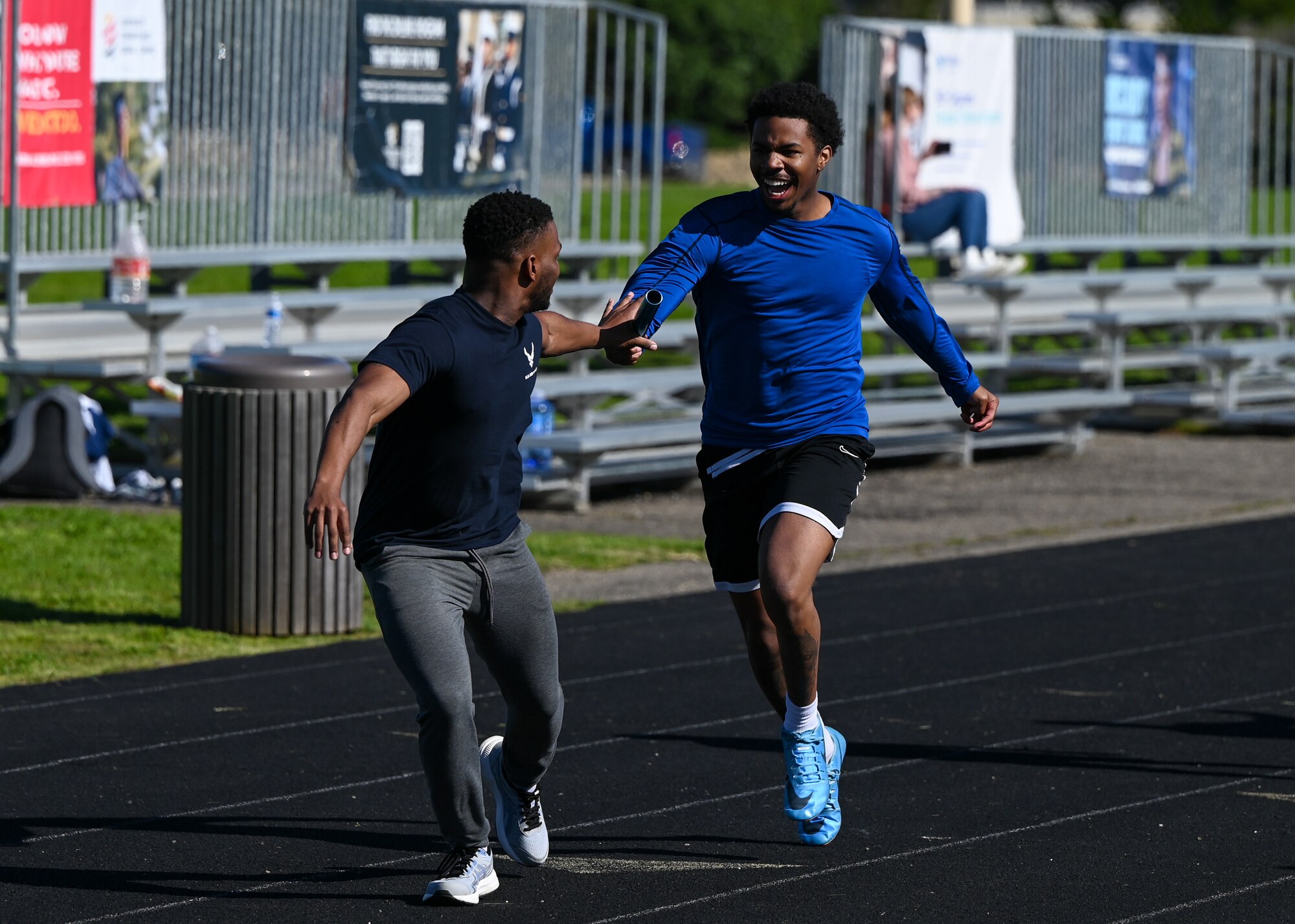 Two Team Blue members engage in the relay race, handing the baton off to the next runner.