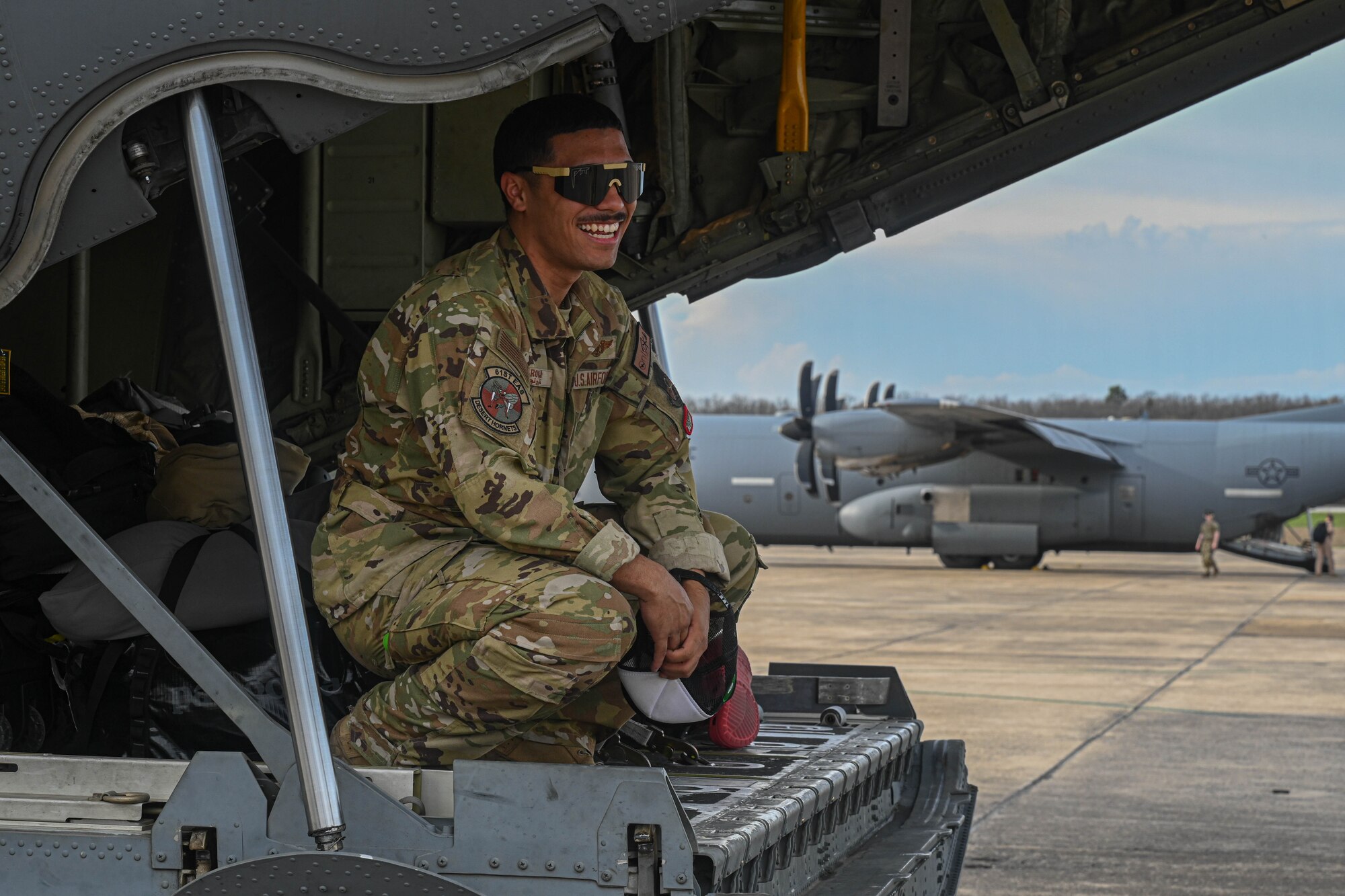An Airman sits on the ramp of an aircraft.